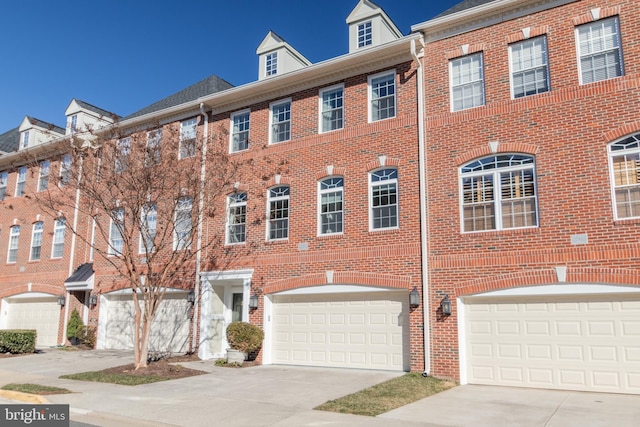 townhome / multi-family property featuring a garage, driveway, and brick siding