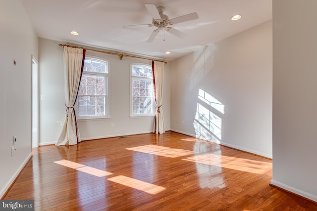 spare room featuring a ceiling fan, baseboards, and hardwood / wood-style floors