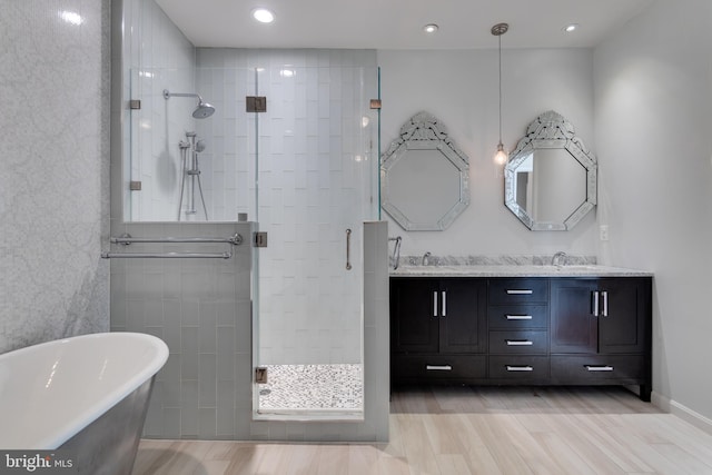 full bathroom featuring double vanity, a soaking tub, wood finished floors, and a shower stall