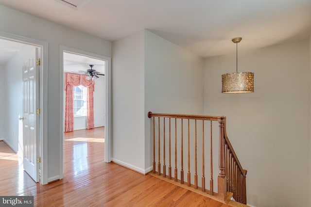 hallway with baseboards, an upstairs landing, and wood finished floors