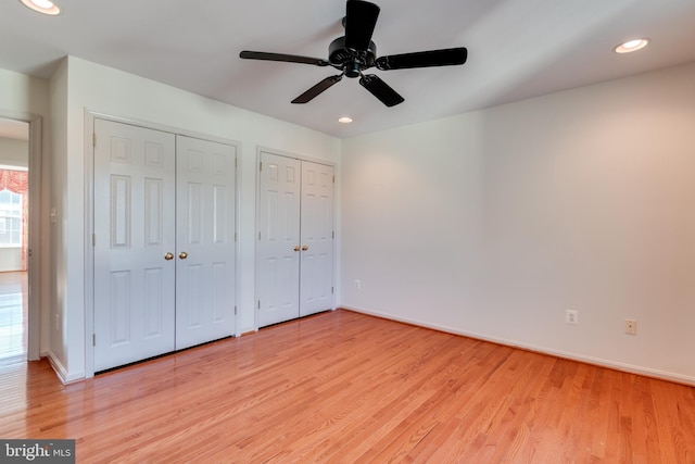 unfurnished bedroom featuring baseboards, multiple closets, ceiling fan, recessed lighting, and light wood-style flooring