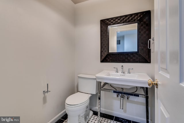 half bathroom featuring toilet, baseboards, and a sink