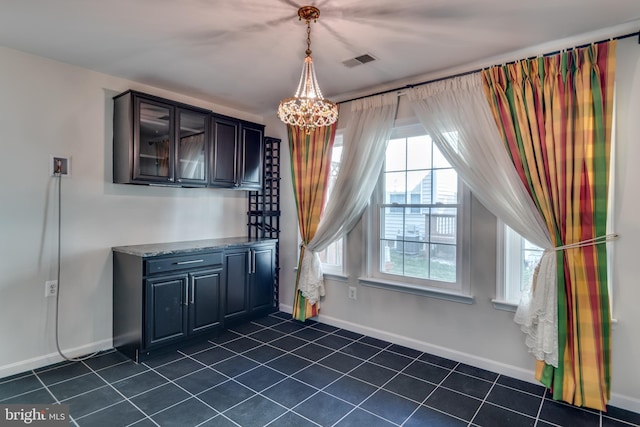 unfurnished dining area featuring visible vents, baseboards, and an inviting chandelier