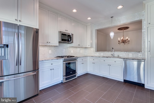 kitchen featuring backsplash, a chandelier, white cabinets, stainless steel appliances, and a sink