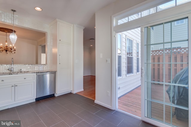 kitchen with a chandelier, dishwasher, decorative backsplash, white cabinets, and a sink