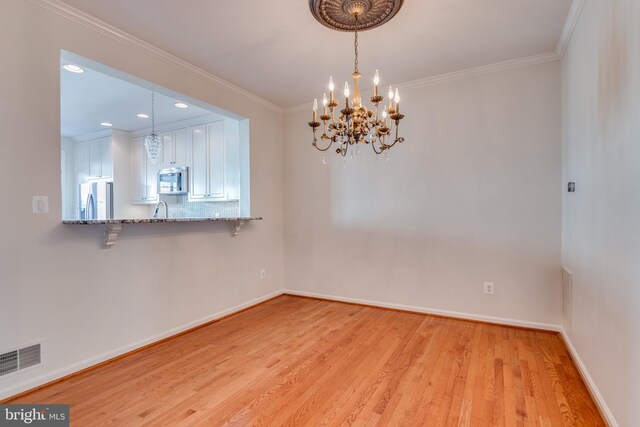 unfurnished room featuring baseboards, visible vents, light wood finished floors, an inviting chandelier, and ornamental molding