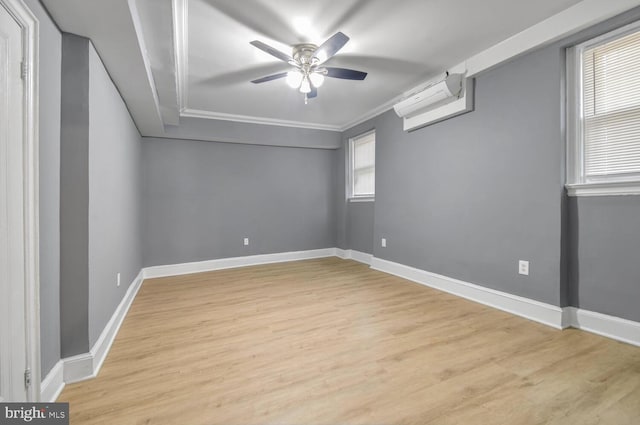 empty room featuring light wood finished floors, crown molding, baseboards, and an AC wall unit