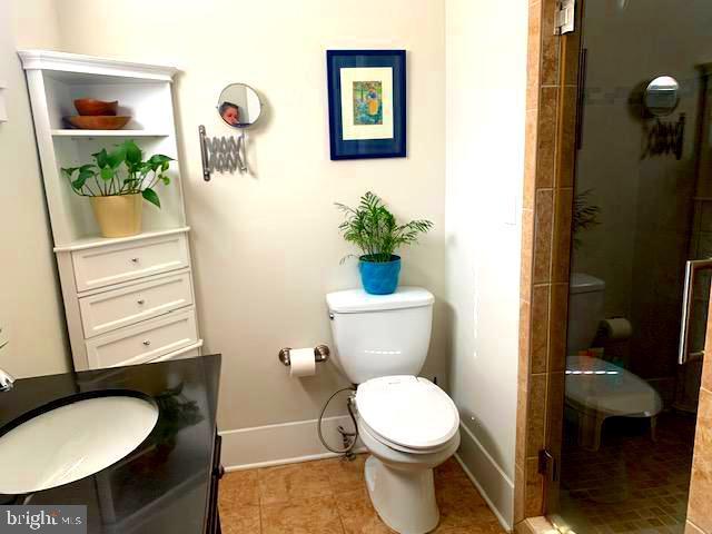 bathroom featuring baseboards, toilet, vanity, and a shower stall