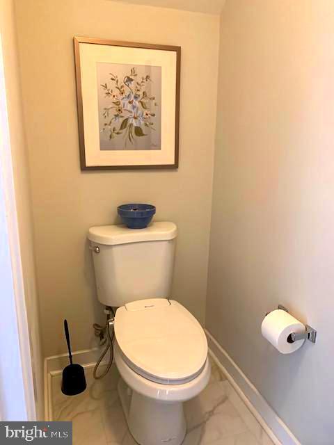 bathroom featuring toilet, baseboards, and marble finish floor