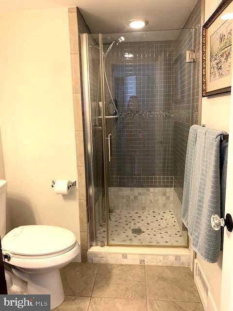 bathroom featuring tile patterned flooring, visible vents, a stall shower, and toilet