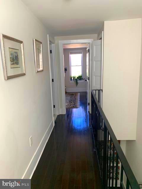 corridor featuring dark wood finished floors and baseboards