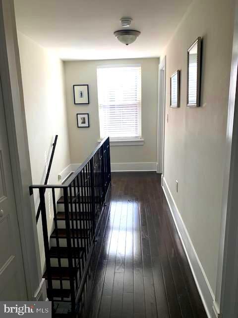 hall featuring hardwood / wood-style floors, an upstairs landing, and baseboards