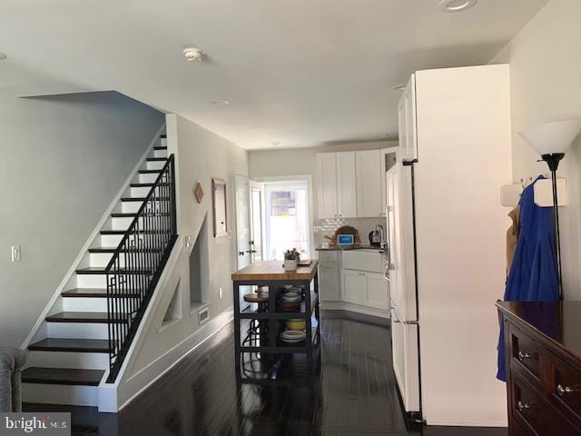 interior space with visible vents, backsplash, white cabinetry, and dark wood-type flooring