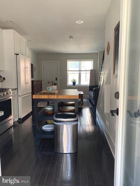 kitchen featuring baseboards, butcher block countertops, appliances with stainless steel finishes, white cabinets, and dark wood-style flooring