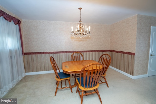 carpeted dining room featuring wallpapered walls, an inviting chandelier, and baseboards