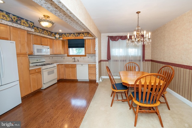 dining space featuring a wainscoted wall, a notable chandelier, light wood-style flooring, wallpapered walls, and baseboards