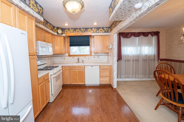 kitchen featuring white appliances, wood finished floors, light countertops, and wallpapered walls