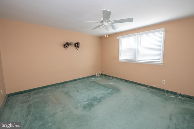 spare room with carpet flooring, visible vents, a ceiling fan, and baseboards