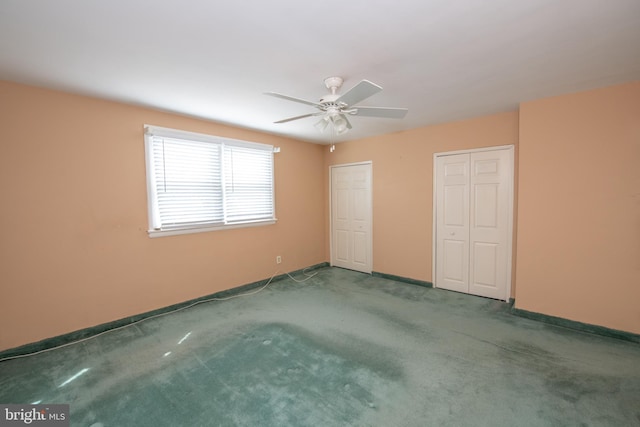 unfurnished bedroom with baseboards, multiple closets, carpet, and a ceiling fan