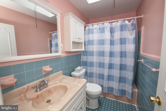 full bathroom featuring toilet, tile walls, wainscoting, and vanity