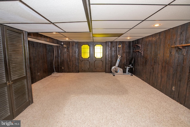 below grade area featuring wood walls, a paneled ceiling, and carpet