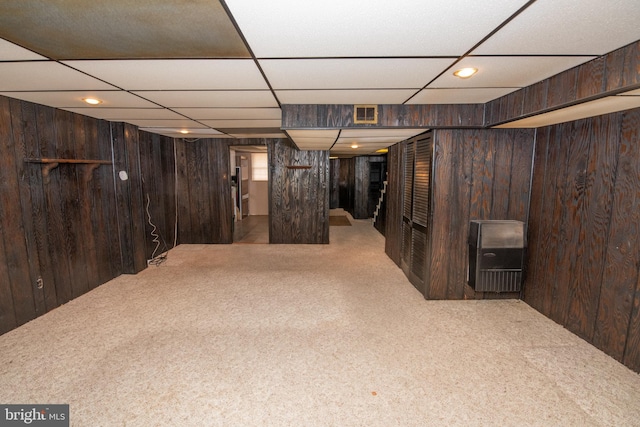 finished below grade area featuring wooden walls, a paneled ceiling, visible vents, and carpet floors