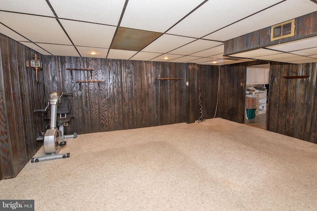 exercise room featuring visible vents, a paneled ceiling, wooden walls, and carpet