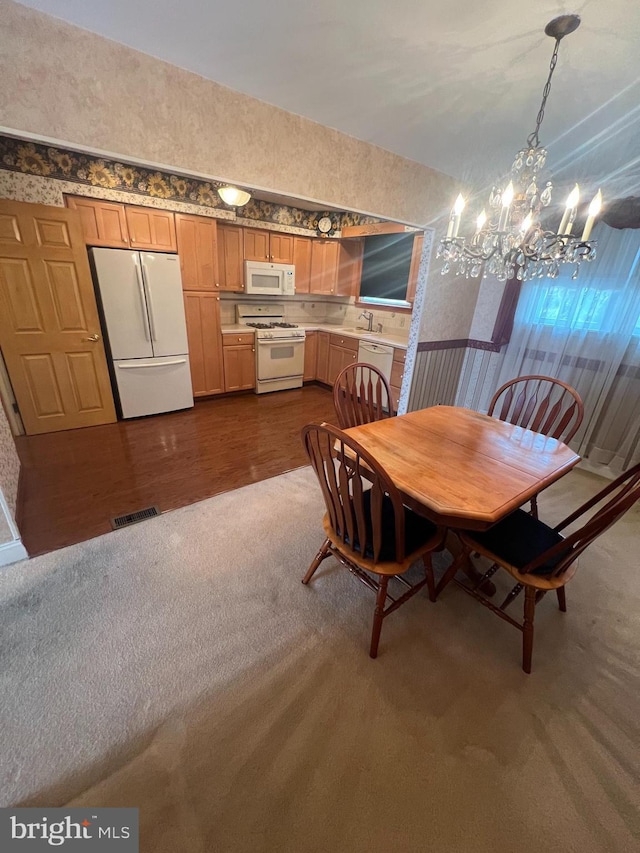 dining area with visible vents, wallpapered walls, dark wood-style flooring, dark carpet, and a chandelier