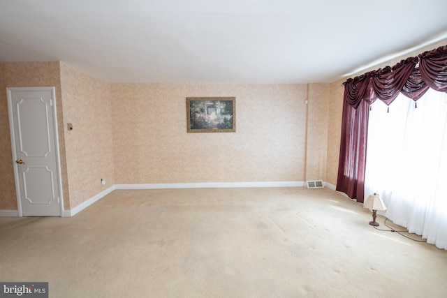 unfurnished room featuring visible vents, light colored carpet, wallpapered walls, and baseboards