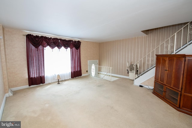 unfurnished living room with carpet, stairs, and wallpapered walls