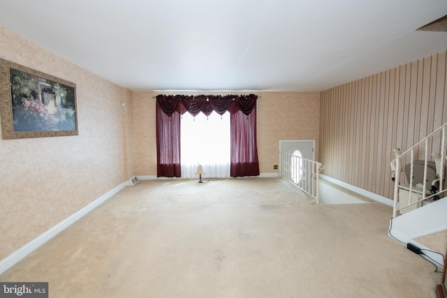 unfurnished living room with carpet flooring, wallpapered walls, and baseboards