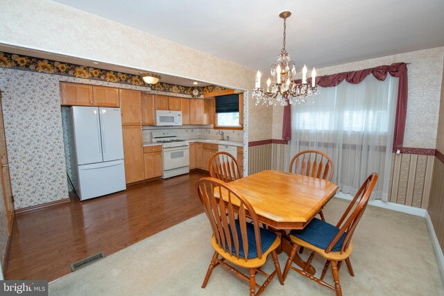 dining room with visible vents, wood finished floors, wallpapered walls, baseboards, and a chandelier