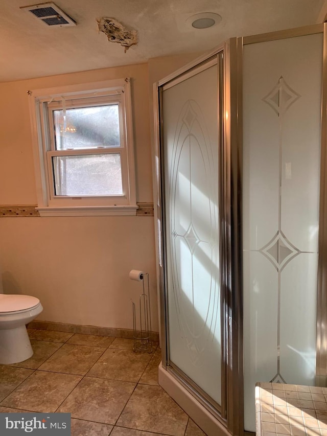 full bathroom featuring toilet, visible vents, baseboards, tile patterned floors, and a shower with door