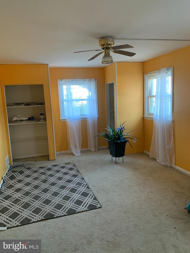 entryway featuring a wealth of natural light, carpet flooring, and ceiling fan