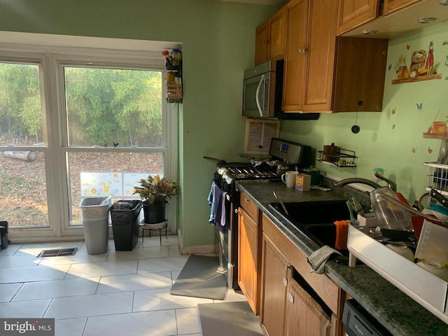 kitchen with light tile patterned floors, visible vents, appliances with stainless steel finishes, and brown cabinets