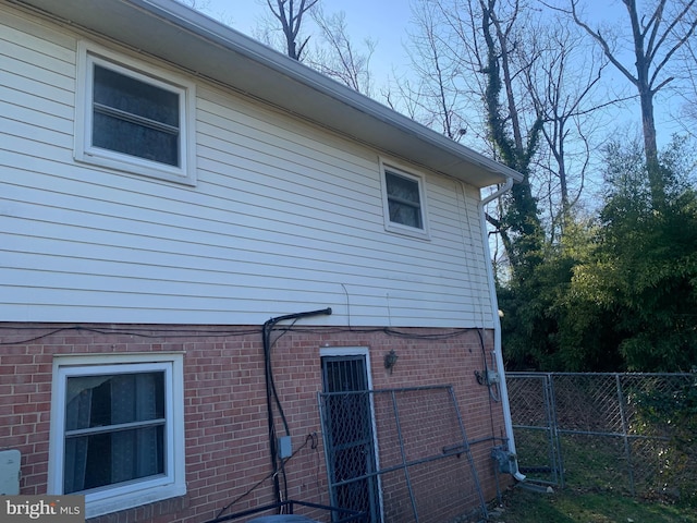 view of property exterior with brick siding and fence