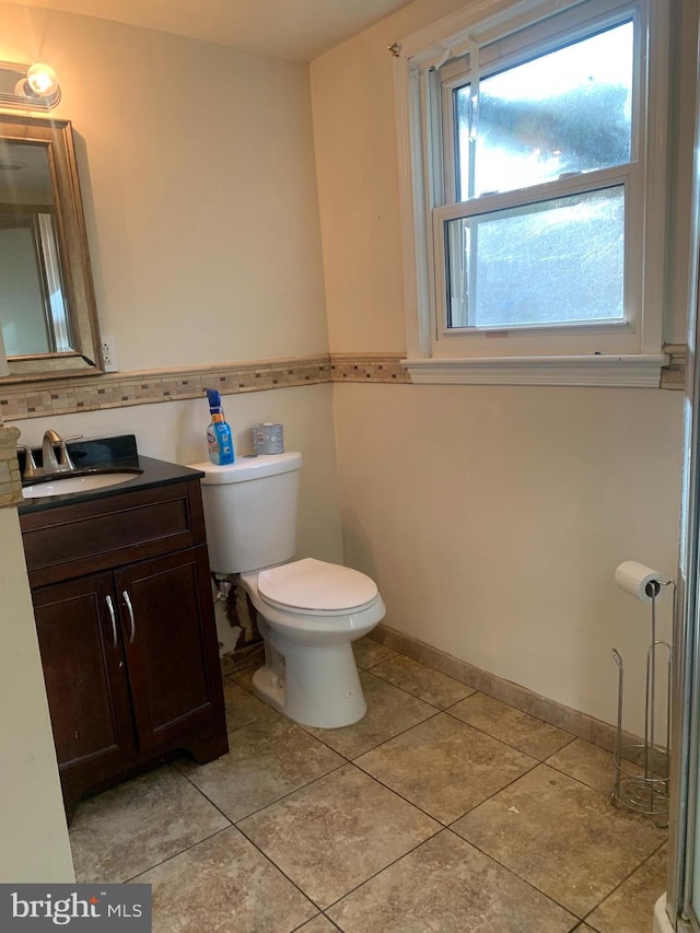 bathroom with tile patterned flooring, baseboards, vanity, and toilet