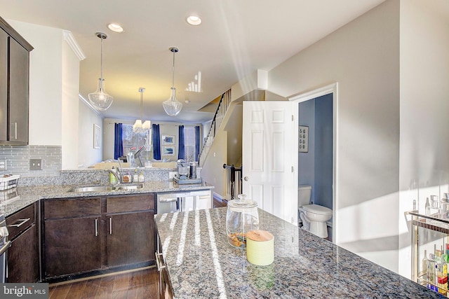 kitchen featuring dark brown cabinetry, tasteful backsplash, light stone counters, and a sink