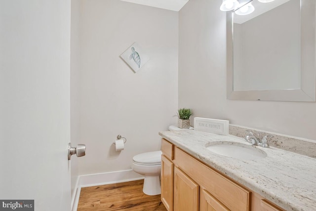 bathroom featuring toilet, vanity, wood finished floors, and baseboards