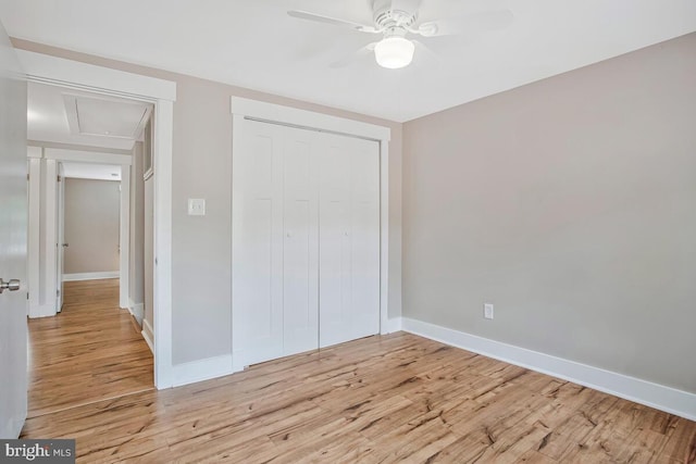 unfurnished bedroom featuring attic access, light wood-style floors, and baseboards