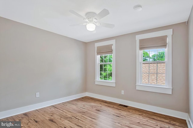 empty room featuring baseboards, wood finished floors, ceiling fan, and a smoke detector
