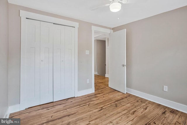 unfurnished bedroom featuring wood finished floors, baseboards, a closet, and a ceiling fan