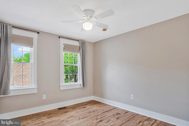 empty room with baseboards, wood finished floors, and a ceiling fan