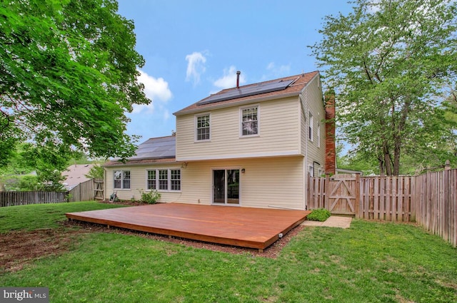 back of house featuring a gate, solar panels, and a wooden deck