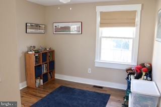 living area featuring wood finished floors, baseboards, and ceiling fan