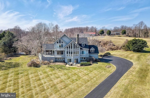 rear view of property featuring a chimney, a balcony, a yard, a patio area, and driveway