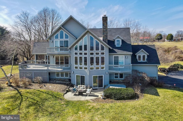 rear view of property featuring a lawn, an outdoor hangout area, a balcony, a chimney, and a patio area