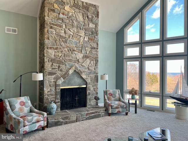 carpeted living area with a fireplace, visible vents, and high vaulted ceiling