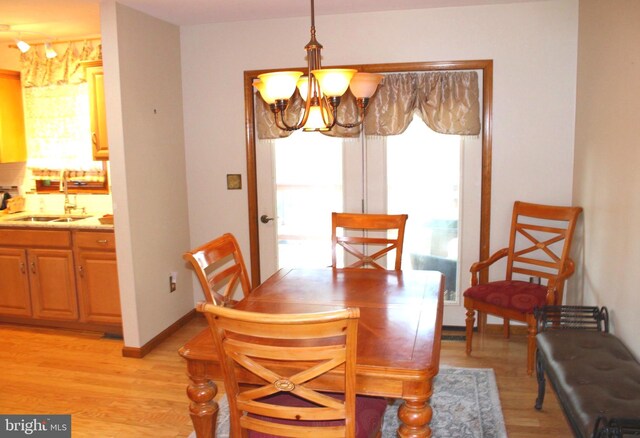 dining area featuring a notable chandelier, light wood-type flooring, and baseboards