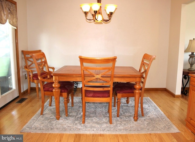 dining space with an inviting chandelier, light wood-style floors, visible vents, and baseboards